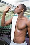 Young shirtless man drinking water at the gym