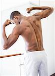 Rear view of a shirtless muscular man flexing muscles in gym