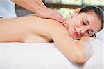 Side view of an attractive young woman receiving back massage at spa center