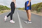 Side view low section of fit young couple standing on the open road together