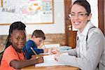 Cute pupil getting help from teacher in classroom at the elementary school