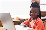 Cute pupil using laptop in classroom at the elementary school