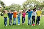 Cute pupils standing on the grass outside  at the elementary school