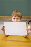 Cute pupil smiling at camera in classroom showing page at the elementary school