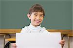 Cute pupil smiling at camera in classroom showing page at the elementary school