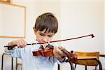 Cute pupil playing violin in classroom at the elementary school