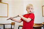 Cute pupil playing flute in classroom at the elementary school
