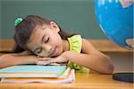 Cute pupil napping in classroom with globe at the elementary school