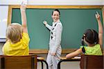 Pretty teacher writing on chalkboard at the elementary school