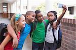 Cute pupils taking a selfie in the corridor at the elementary school