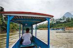 Nong Khiaw, Luang Prabang Province. Two riverboats pass each other on a rough stretch of the Nam Ou river. The wheelhouse in the bows of these boats is only just big enough to accommodate the helmsman.