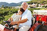 Grandfather and boy sitting on tractor