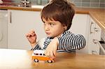 Boy pushing toy car on kitchen surface