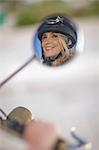 Face of a woman with helmet in rear mirror