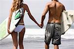Guy and girl walking with surfboards