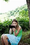 Girl under tree playing with make-up