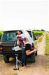 Newlywed couple kissing by vehicle