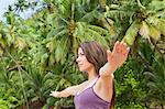 Woman practicing yoga by palm trees