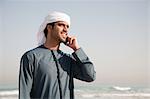 Middle Eastern man using mobile phone on the beach