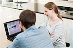 Young couple looking at travel insurance on laptop