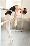 Ballerina leaning over barre