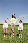 Mother with two children in field with arms up