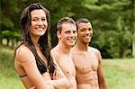 Three teenagers in swimming costumes relaxing together