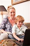 Young boy using laptop with mother looking on encouragingly