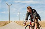 Man on bicycle in front of wind turbines