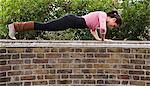 Woman performing push ups on top of wall