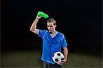 Young soccer player pouring water of himself on pitch