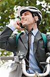 Mid adult businessman using cellphone on bicycle