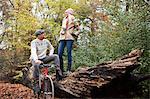 Man with bike and woman standing on log