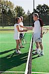 Senior and mature adults shaking hands on tennis court