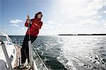 Young woman holding onto rope on  yacht