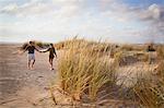 Mid adult couple holding hands on beach