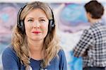 Mid adult woman wearing headphones in gallery