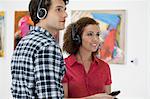 Young couple using audio guides in art gallery