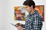 Young man using digital tablet in art gallery