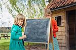 Two girls outdoors with blackboard