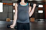 Pregnant young woman with hand weights