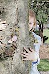 Woman peeking out from behind tree