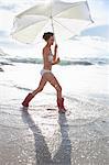 Woman carrying umbrella on beach