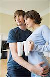 Couple hugging with coffee in new home