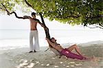 Couple talking under tree on beach