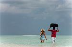 Couple carrying luggage into sea