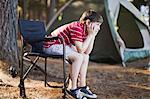 Bored boy in lawn chair at campsite