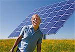 Man standing in field by solar panel