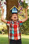 Boy holding birdhouse on his head