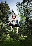 Girl wearing wings and jumping in forest